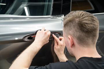 Car wrapping, detailing, tuning and styling. Detailer smoothes PPF. A car wrapping specialist...