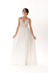 Fototapeta premium Elegant model showcases a flowing white gown with intricate detailing in a soft studio setting