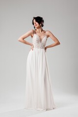 Elegant model showcasing a white evening gown during a fashion shoot in a studio setting