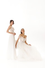 Fototapeta premium Bridal models showcase elegant wedding dresses in a studio setting during a fashion shoot