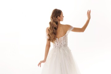 Model showcases elegant wedding dress with intricate lace details in a bright studio setting
