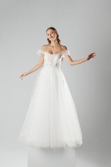 Fototapeta premium Stylish model showcases elegant white wedding dress in minimalist studio setting during fashion presentation
