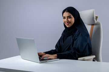 A collection of images of Arab business professionals, both male and female, in traditional clothing working together in a modern office setting, using laptops, discussing projects, and collaborating 