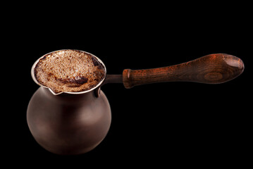 Coffee prepared in a Turk on a black background.