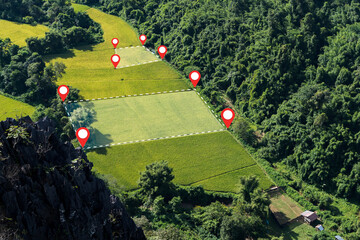 Aerial view of rice fields with location pins and boundary lines in tropical mountain valley...