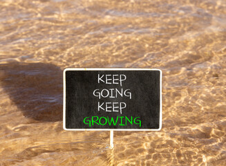 Naklejka premium Keep going and growing symbol. Concept words phrase Keep going keep growing on beautiful black blackboard. Beautiful Red sea water background. Business Keep going and growing concept. Copy space.