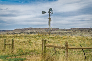 A windmill and barbed wire fence in the Montana landscape.