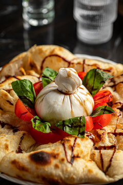 Portion of italian style focaccia with buratta cheese and tomatoes