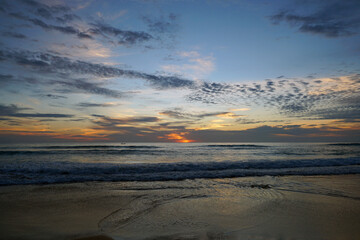 Obraz premium Serene Sunset Over Tranquil Ocean Waves Reflecting Vibrant Colors in Early Evening Sky