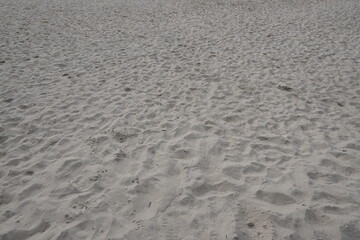 Textured Sand Surface with Footprints and Small Debris on a Beach Landscape