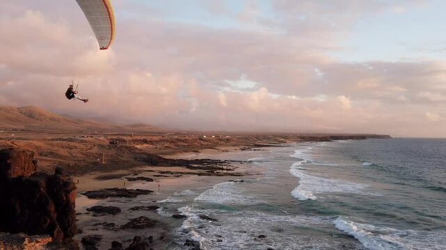 Gleitschirm fliegt &uuml;ber Meer und K&uuml;ste im Abendlicht, Fuerteventura