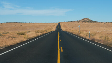 Driving on highway of black asphalt and yellow road markings, pass through desert prairie with dried yellow grass, in western usa national park. Slow motion, view from car. Cargo delivery goods