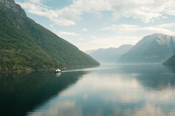 View of a Ferry from the town Hellesylt to Geiranger with the sunnylvsfjord in the background and the entrance to the Geirangerfjord.