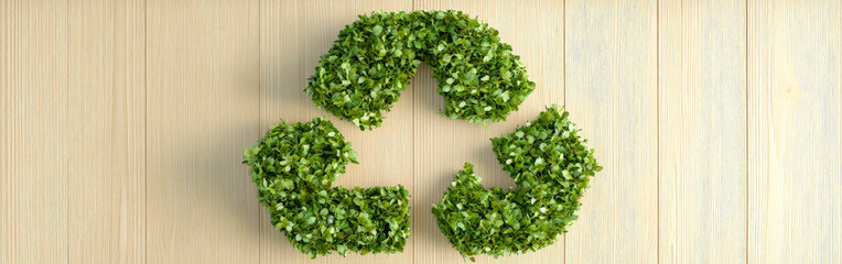 Recycling symbol made of green leaves on wooden background