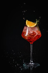 Aperol spritz cocktail in a glass with ice and orange on a black background