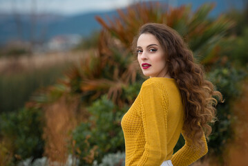 Smiling woman in mustard yellow knit sweater enjoying autumn outdoors