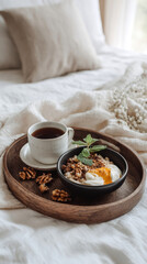 Fototapeta premium A delightful seasonal breakfast features a bowl of oatmeal topped with nuts and fresh mint next to a steaming cup of tea on a wooden tray in a cozy setting