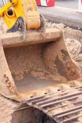 Close-up of excavator bucket. Excavator levels the ground on the site. Repair work in the city. Specialized equipment. Industrial, construction and urban projects. Equipment on the construction site