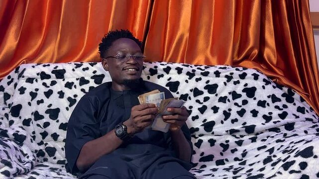 human counting cash sitting in a comfy couch 