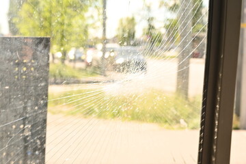 shattered safety glass on a public transport bus stop. The cracks form a circular spiderweb...