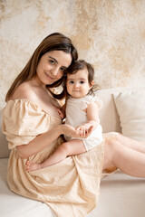 a mother with a baby, a young mom gently hugs and kisses her newborn baby, holding him in her arms, maternal love and care, a mother having fun with her child at home