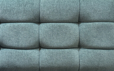 Fototapeta premium Close up of blue fabric upholstered panel with cushion and padded wall. Suitable for sofa backing, upholstery, and other soft seating. Seamless background texture.