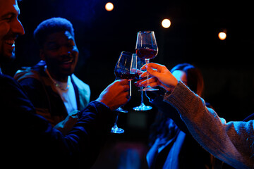Friends celebrating with drinks at night in a lively atmosphere amidst soft blue lights