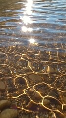 Clear water ripples softly while sunlight glimmers on its gentle surface. Vertical.