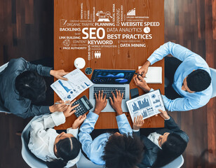 A top-down view of a team engaged in an SEO strategy meeting with laptops, charts, and planning...
