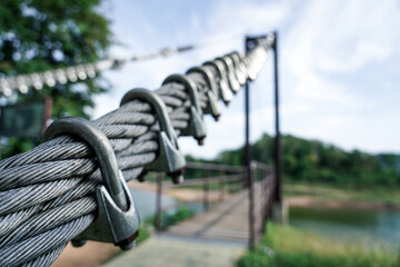 Steel wire rope hook with belt strap power cord, structure of suspension bridge railing. Close up.