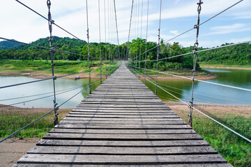 Wooden footbridge in nature tropical forest for trail route. Walking swing bridge, a suspension bridge across jungle, path way at Kaeng Krachan National Park, Phetchaburi Province,Thailand.