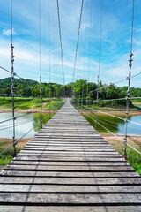 Wooden footbridge in nature tropical forest for trail route. Walking swing bridge, a suspension bridge across jungle, path way at Kaeng Krachan National Park, Phetchaburi Province,Thailand. Vertical.