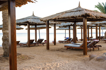 Peaceful beachside cabanas provide shade for relaxation near the ocean during sunset