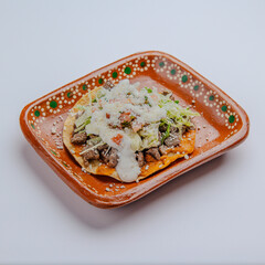 Authentic Mexican tostadas on handmade clay plate, isolated on white background &ndash; traditional and rustic street food