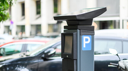 Solar-powered parking meter stands prominently in a busy urban area filled with parked vehicles, showcasing modern infrastructure