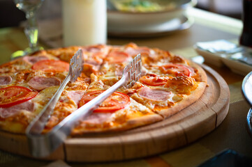 Delicious pizza on a wooden tray on a table in a cafe