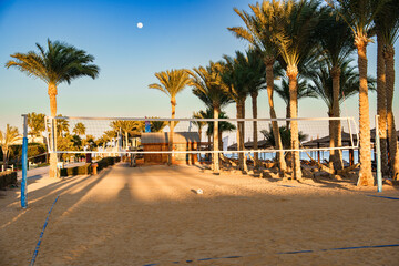 Obraz premium Volleyball court surrounded by palm trees and beach at sunset near tropical resort