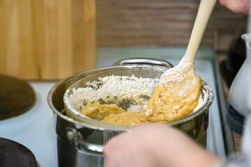 Honey dough being stirred on a double boiler with a silicone spatula, showcasing a traditional baking technique