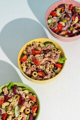 Balanced diet - Healthy tuna salads mixed with macaroni, lettuce, cheery tomato, peas and beans cucumber on white background. 
