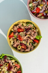 Balanced diet - Healthy tuna salads mixed with macaroni, lettuce, cheery tomato, peas and beans cucumber on white background. 