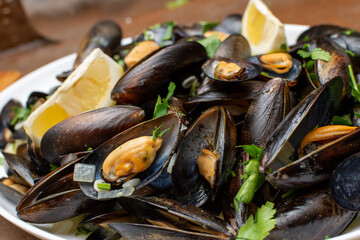 A white plate beautifully topped with succulent mussels and fresh lemon slices