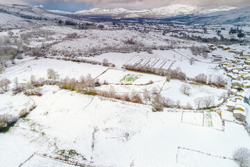 winter in galicia, snow covered rural landscape and mountains, drone view