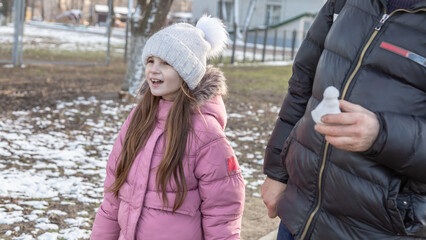Grandfather walks with his granddaughters after school in the park in sunny winter day