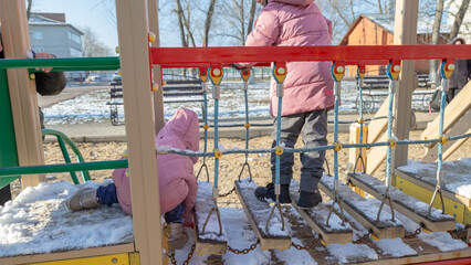 Grandfather with grandchildren playing on the playground on a cold winter day