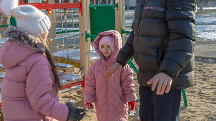 Grandfather with grandchildren playing on the playground on a cold winter day