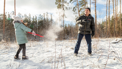 Playful family enjoying snowball fight in snowy winter park
