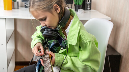 Little girl playing electric guitar on at home
