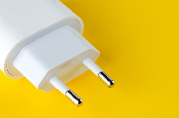White electrical plug adapter on yellow background, close-up view