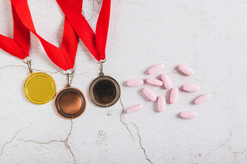 Medals and doping pills on gray background top view