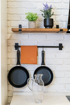  Stylish Kitchen Arrangement with Shelves and frying pans on a white brick wall